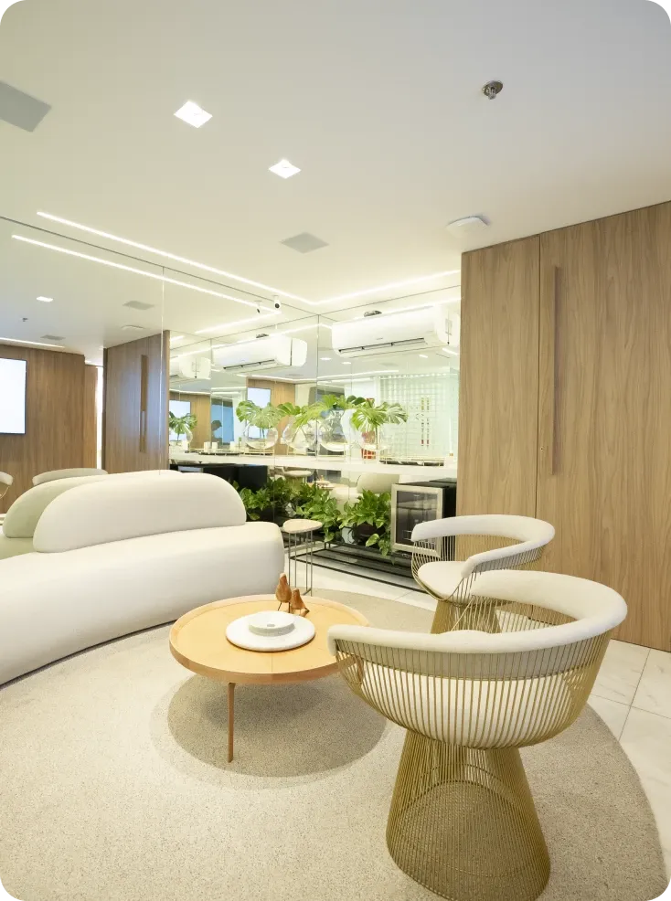 Sala de espera da clínica com sofá claro, poltronas e mesa de centro
