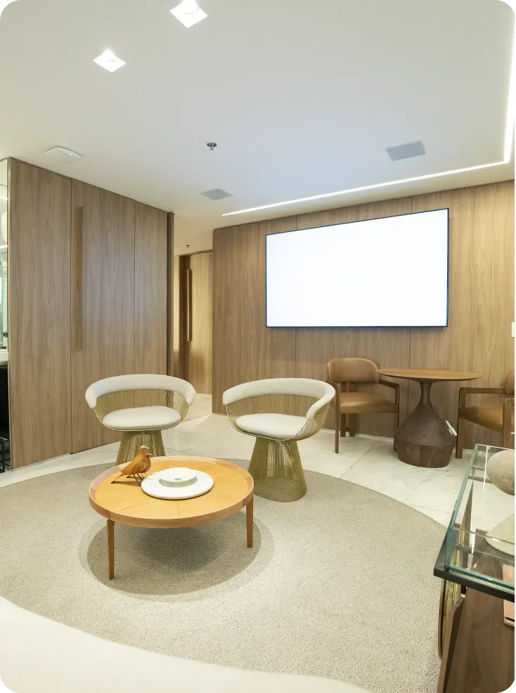 Ambiente de convivência da clínica com poltronas, mesa de centro e painel de madeira